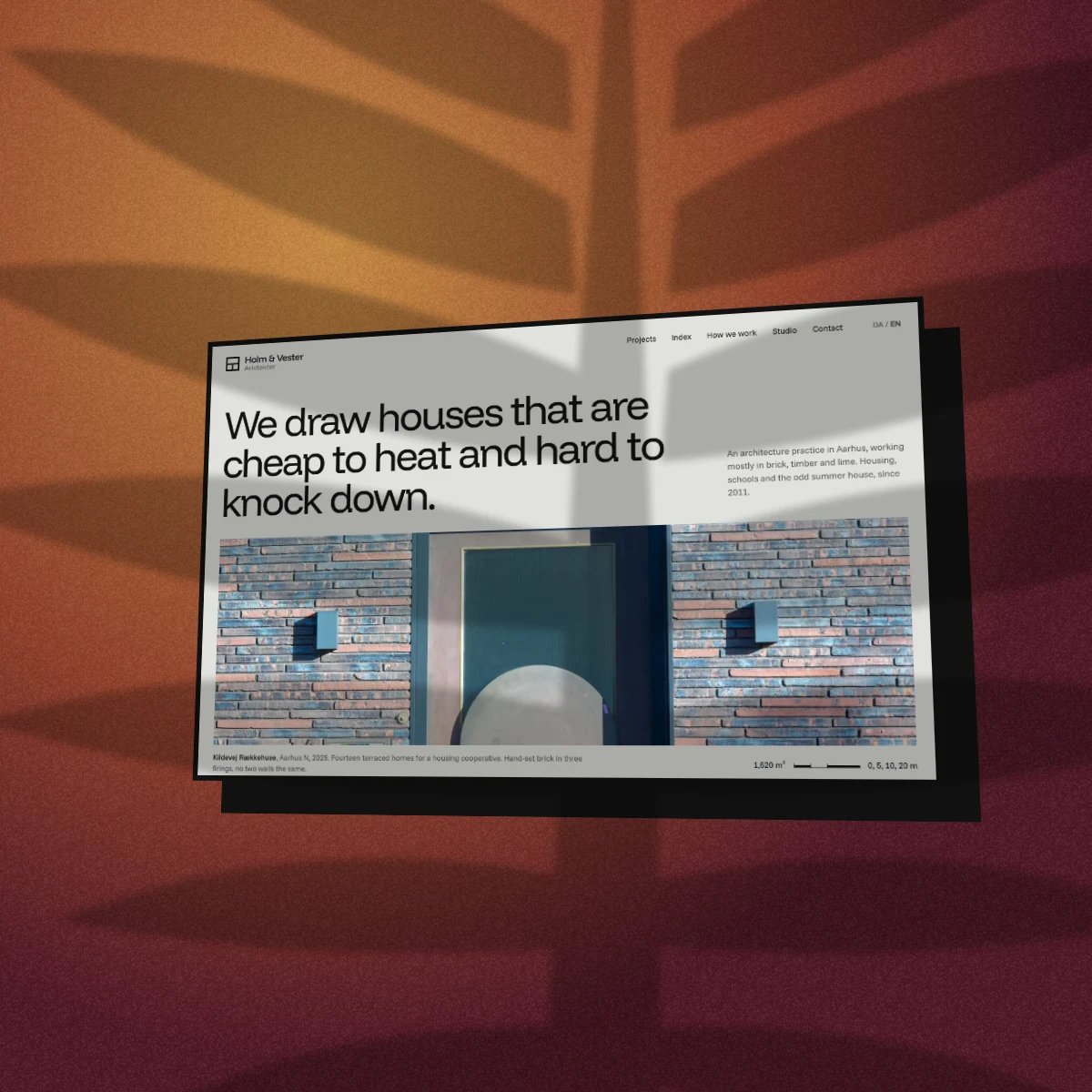 The Holm & Vester homepage with no device frame, tilted, with a chunky ink retro offset, on brick red studio light with a palm shadow thrown across it