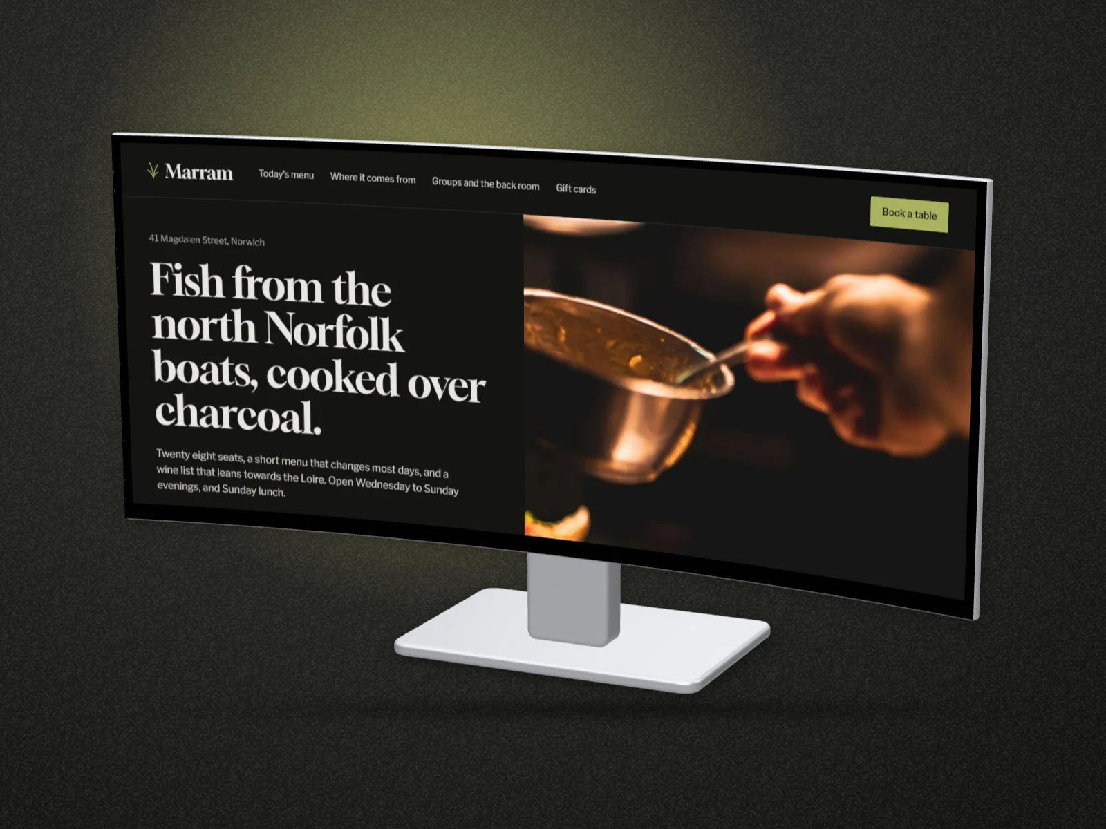 marram.kitchen, a restaurant's homepage, stretched across a curved 3D Dell ultrawide monitor on its stand, under a soft spotlight